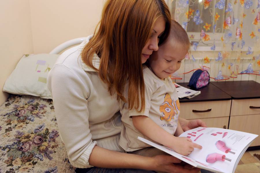 Eine junge Mutter schaut sich mit ihrem Kind ein Bilderbuch an.