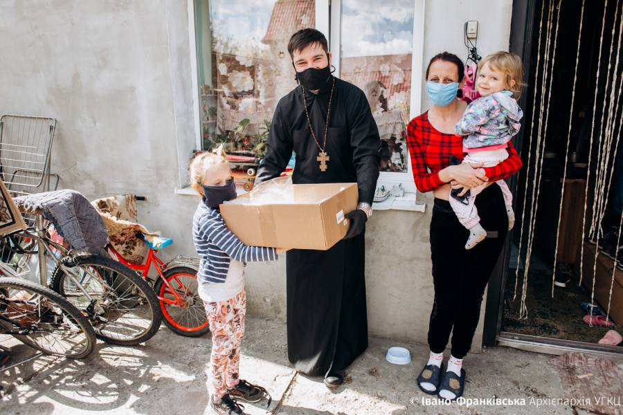 Ein Priester bringt eine Hilfslieferung an eine Frau mit zwei kleinen Kindern.