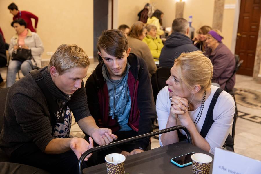 Liza Levchenko sitzt zusammen mit zwei Jugendlichen, interessiert sich für das, was sie beschäftigt und gibt ihnen Tipps für die Zukunft.