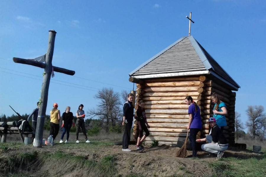 Jugendliche helfen tatkräftig mit beim Bau der hölzernen Kapelle in Muratowe; nebenstehend ein großes Kreuz .