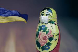 Collage: Flagge der Ukraine, Matrioschka-Puppe mit Mundschutz