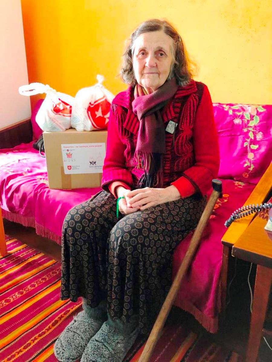 Alte Frau sitzt im Wohnzimmer mit den Paketen der Malteser.