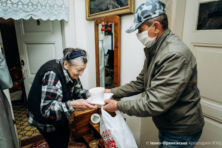 Junger Priester bringt einer alten Frau ein warmes Essen.