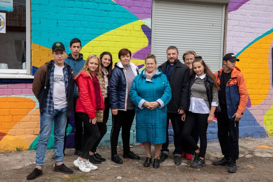 Jugendliche zusammen mit zwei Mitarbeitenden der Caritas Severodonetsk vor einem neu eröffenten Begegnungszentrum in Borivske.