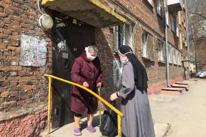 Eine Ordensfrau bringt einer bedürftigen Frau eine Tüte mit Lebensmitteln