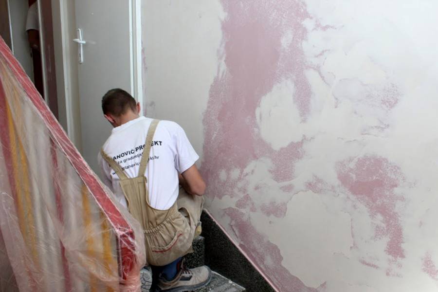 Ein junger Mann repariert eine Wand im Treppenhaus des Kinderheims.