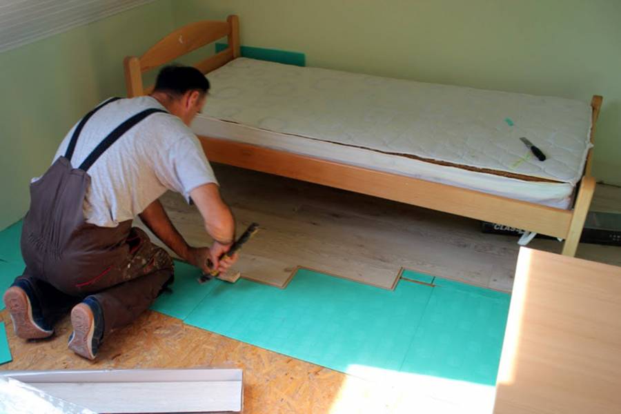 Ein Arbeiter verlegt neuen Fußboden in einem der Kinderzimmer.