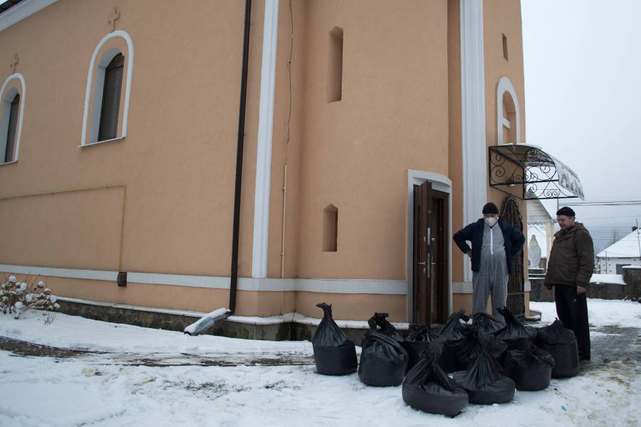 Zwei Männer vor einer Kirche mit vielen Säcken mit Fledermausmist