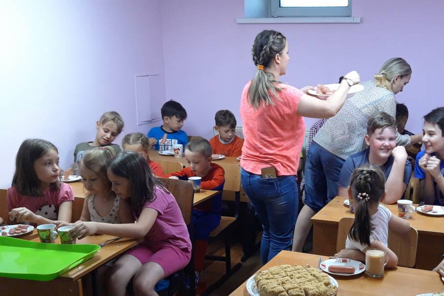 Kinder bekommen einen Imbiss in einem kleinen Klassenraum.