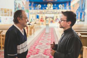 Priester und Gemeindemitglied im Gespräch in einer griechisch-katholischen Kirche