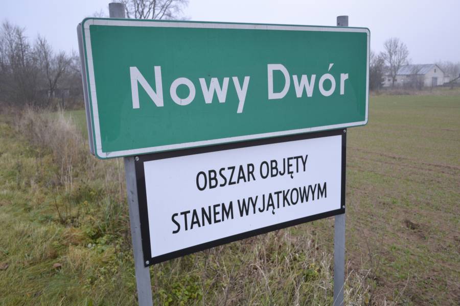 Ortschild der Gemeinde Novy Dwór - ein weiteres Schild weist darauf hin, dass in der Region der Ausnahmezustand verhängt wurde.