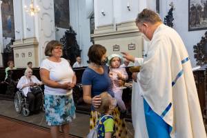 Priester im Gottesdienst mit einer Familie mit kleinen Kindern