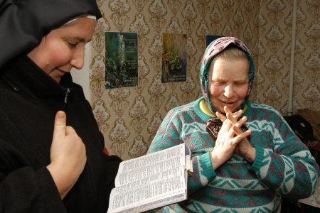 Ordensschwester betet mit einer alten Frau