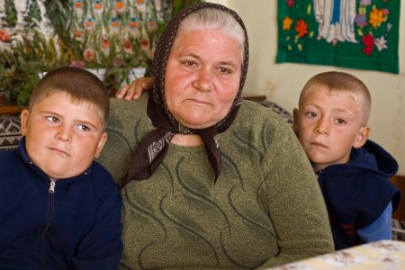 Oma sitzt mit zwei Enkeln auf dem Sofa