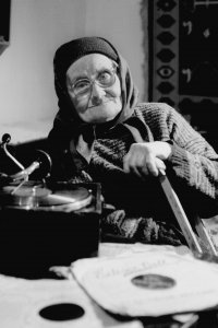 Alte Frau hört Musik mit Grammophon