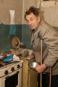 Alter, armer Mann auf Krücken in Küche