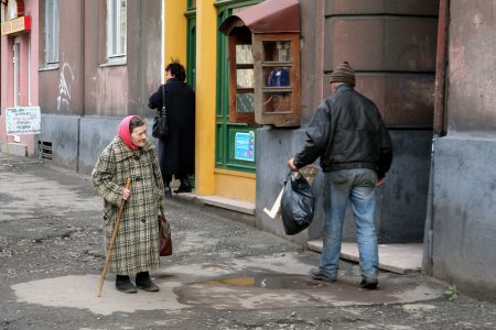 Alte Frau geht auf einer verfallenen Straße