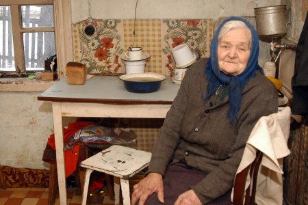 Alte, arme Frau sitzt in der Küche