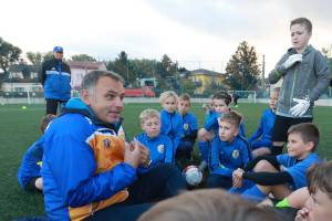 Der Priester Tibor Reimer sitzt im Trikot mit Jugendlichen auf dem Fußballplatz