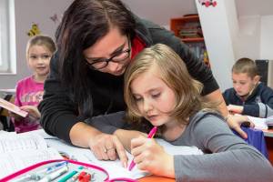 Lehrerin hilft Schülerin bei Hausaufgaben.