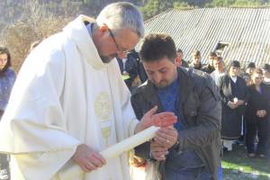 Priester und ein Laie zünden eine Kerze an.