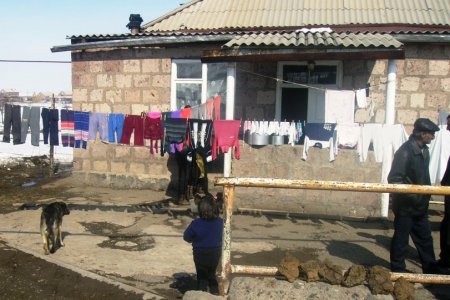 Wäsche trocknet auf einer Wäscheleine vor einem sehr einfachen Haus in Armenien.