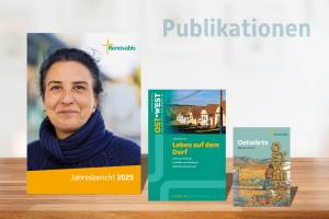 Drei Renovabis-Publikationen stehen nebeneinander auf einer hellen Holzfläche vor unscharfem Hintergrund. Links der Jahresbericht 2025 mit einem Porträtfoto auf dem Titel und dem Schriftzug „Jahresbericht 2025“. In der Mitte die Zeitschrift „OST‑WEST. Europäische Perspektiven“ mit dem Titelthema „Leben auf dem Dorf“ und einem Foto von Häusern in ländlicher Umgebung. Rechts die Publikation „Ostwä rts – Warum nicht?“ mit einer illustrierten Landschaft und einer gehenden Person. Über den Publikationen steht groß das Wort „Publikationen“.