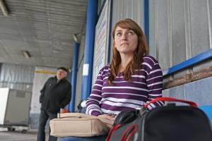 Wartende Frau mit Koffern am Busbahnhof
