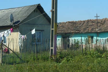 Zwei sehr einfache Häuser, im Vordergrund eine Wiese und ein Strommast.