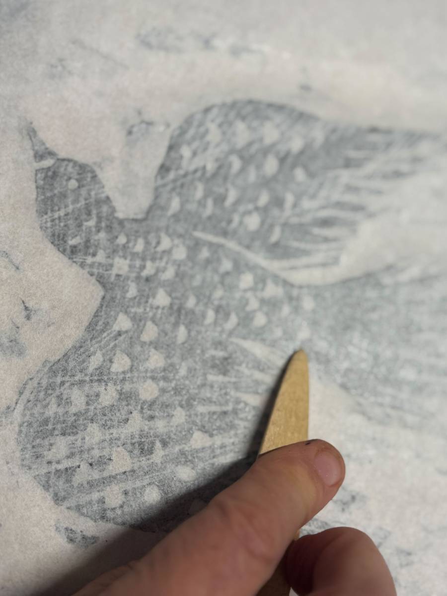 Japanpapier wird auf den Druckstock aufgelegt und mit einem Falzbein abgerieben.