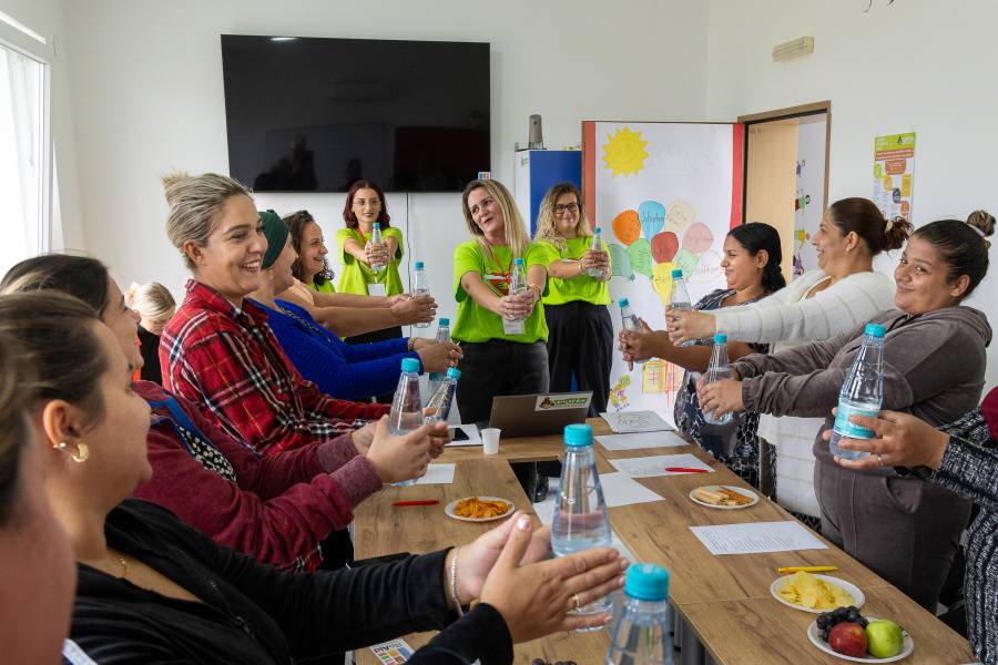 Rund ein Dutzend Frau treffen sich im Concordia-Zentrum in Gjakova. Sie sehen um einen Tisch mit Papier und Stiften herum und halten jeweils eine gefüllte Wasserflasche mit ausgestreckten Armen vor sich - eine Entspannungsübung.
