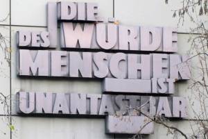 Das Foto zeigt Artikel 1 des Grundgesetzes "Die Würde des Menschen ist unantastbar" in großen Steinbuchstaben an der Fassade des Landgerichts in Frankfurt am Main.