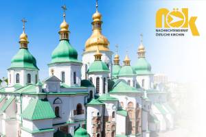 Auf dem Bild ist die Sophienkathedrale in Kyjiw, Ukraine, zu sehen. Die Kirche hat weiße Wände, grüne Dächer und mehrere goldene Kuppeln mit orthodoxen Kreuzen. Der blaue Himmel verstärkt den klaren, leuchtenden Eindruck. Rechts oben ist das gelbe Logo des Nachrichtendienstes Östliche Kirchen (NÖK) eingebaut.