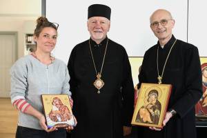 Das Bild zeigt drei Personen, die nebeneinander stehen: Links die Projektreferentin Katharina Ebel, in der Mitte den ukrainischen Erzbischof Vityshyn und Prof. Thomas Schwartz. Frau Ebel und Herr Schwartz halten Gemälde in der Hand, die ukrainische Ikonen zeigen.