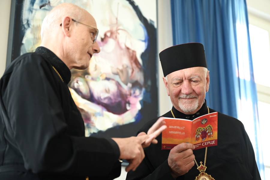 Das Bild zeigt links Prof. Thomas Schwartz, im Gespräch mit Erzbischof Vityshyn auf der rechten Seite, der amüsiert im Renovabis-Gebetsheft "Öffne mein Herz" in ukrainischer Sprache blättert.