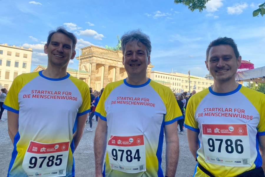 Drei Männer in gelb-weiß-blauen Trikots mit Startnummern, die für Renovabis am Berliner Firmenlauf teilnehmen. Das Bild zeigt von links nach rechts Matthias Dörr, Leiter der Abteilung Kommunikation und Kooperation, Geschäftsführer Dr. Markus Ingenlath sowie Nicolas Riedmiller, Referent im Team der Öffentlichkeitsarbeit.