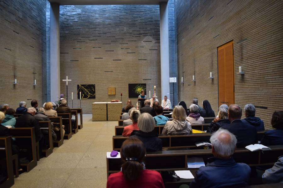 Das Bild zeigt die gut gefüllte Kirche St. Thomas v. Aquin in Berlin. Die Wände sind mit hellbraunen Klinkersteinen verkleidet, der Altarraum ist sehr schlicht gehalten. In den Bänken beten Spenderinnen und Spender von Renovabis, die das Hilfswerk zu einem Spendertreffen eingeladen.