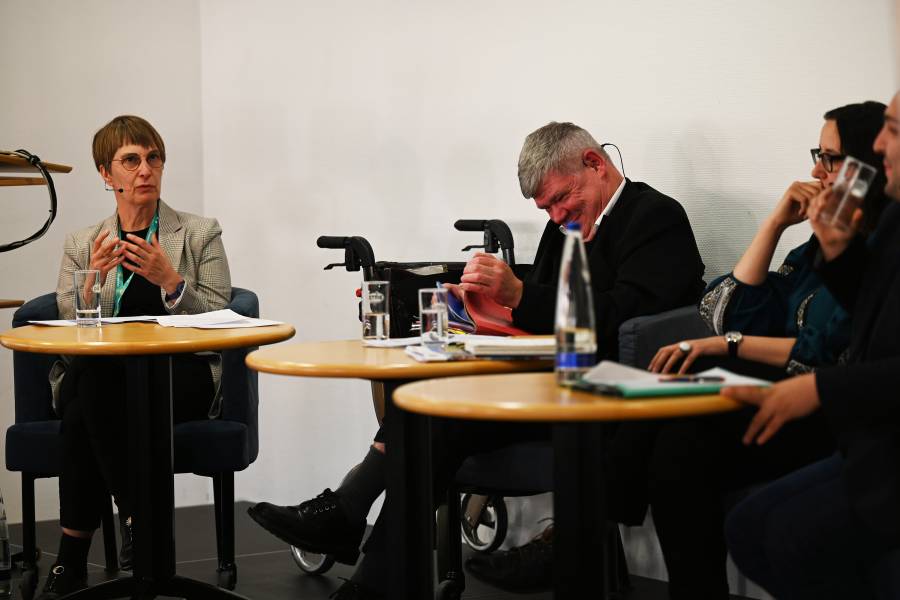 Das Bild zeigt eine Podiumsdiskussion in der Katholischen Akademie in Berlin. Über die Situation von geflüchteten Menschen aus der Ukraine sprachen mit Moderatorin Renate Krekeler-Koch (Renovabis) - sie trägt kurze, dunkle Haare, eine Brille und einen beigen Blazer - xxx