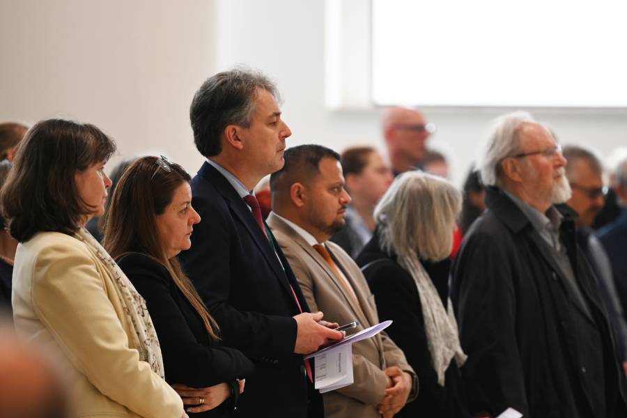 Drei Frauen und drei Männer, die den Eröffnungsgottesdienst der Renovabis-Pfingstaktion besuchen. Sie stehen und hören mit ernstem Blick zu.