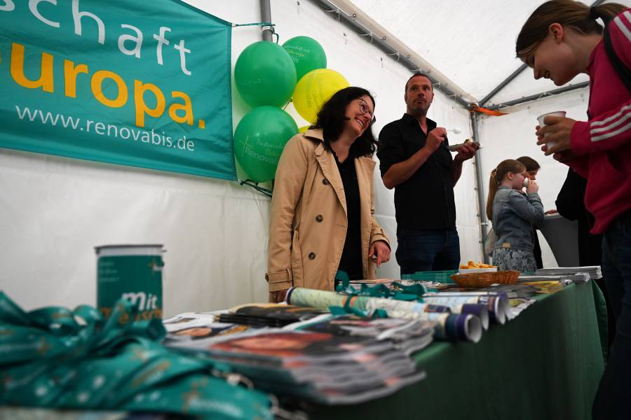 In einem weißen Zelt steht der Stand von Renovabis mit zahlreichen Materialien wie Broschüren, Schlüsselbändern, Bonbons und einer Spendenbox. Im Hintergrund ein Banner mit Renovabis-Aufdruck.