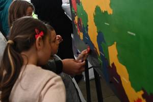 Kinder stehen vor einer Wand, auf der sie die Länder Osteuropas aneinander puzzeln können. Gemeinsam überlegen sie, welches Land wo hin gehört.