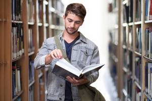 A young man reading in a library. A Renovabis scholarship facilitates studies or vocational training.