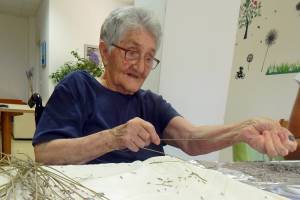 Bewohnerin eines Seniorenheims sitzt am Tisch putzt Lavendel.