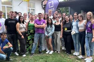 Gruppenfoto mit jungen Frauen und Männern in einem Garten, im Hintergrund ist ein Haus zu sehen.