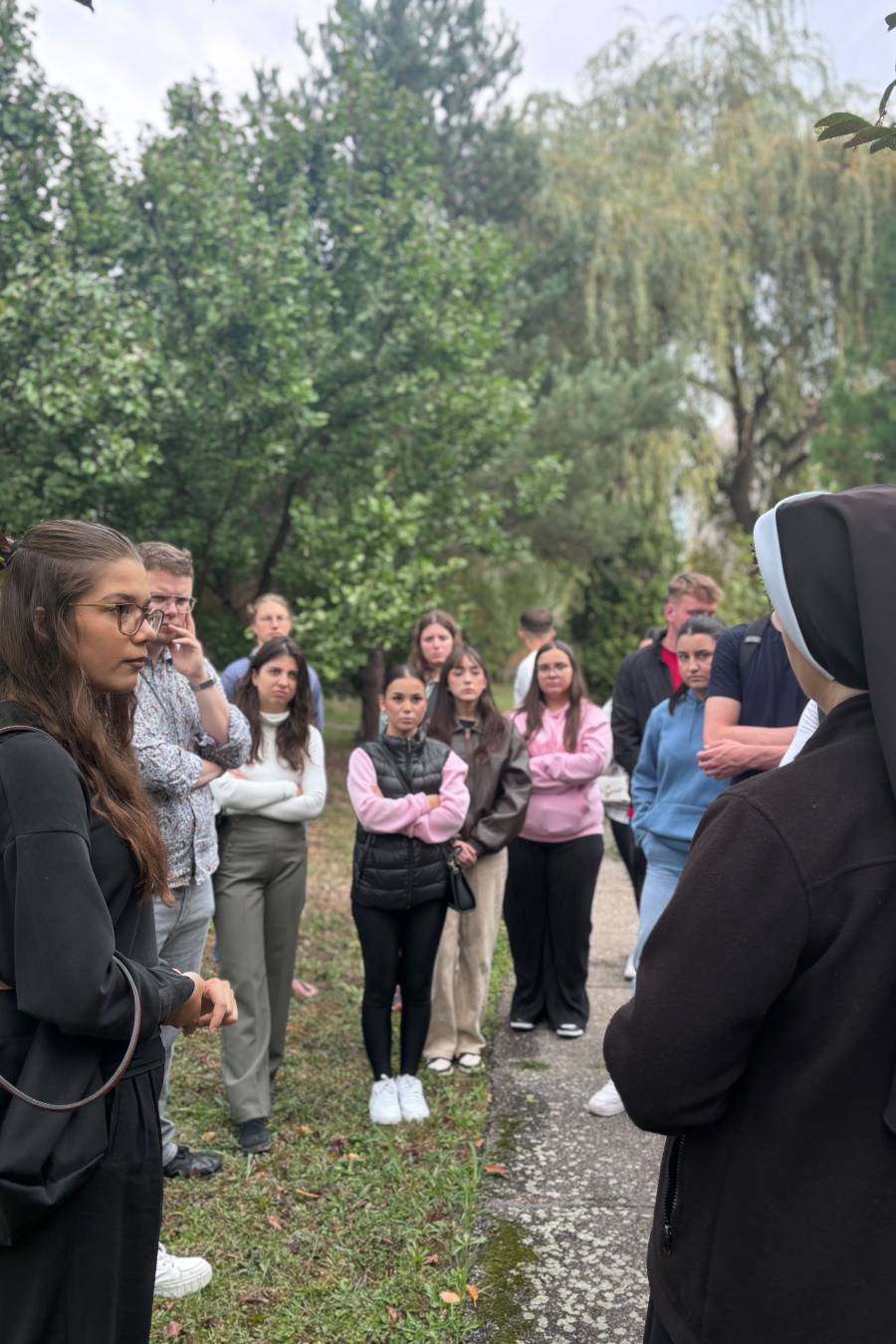 Junge Frauen und Männer stehen in einem Garten und sprechen mit einer Ordensfrau, einer Franziskanerin, die das Hospiz in Timișoara betreut.