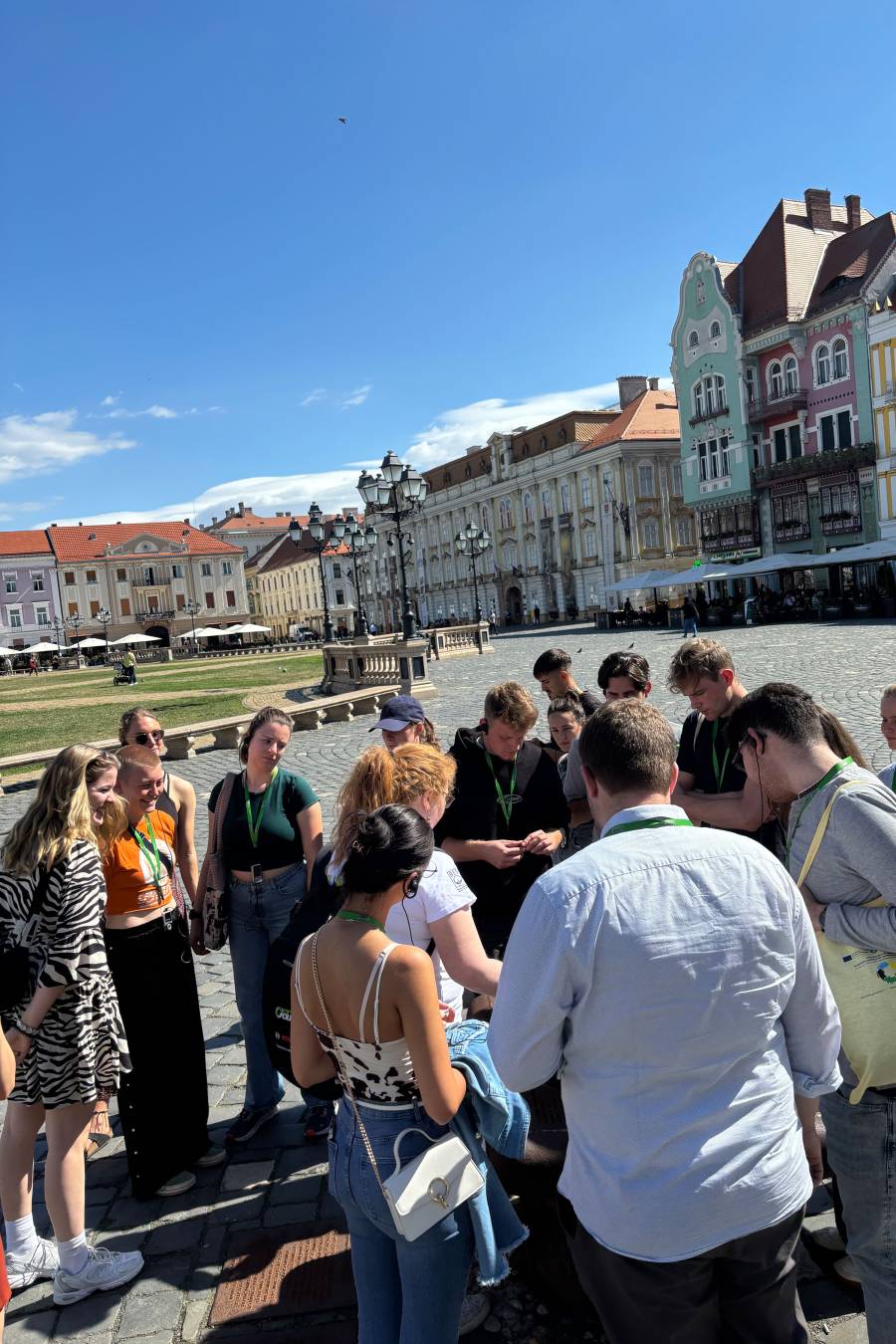 Die Frauen und Männer stehen auf dem zentralen Platz in Timișoara, im Hintergrund schöne alte Gebäude