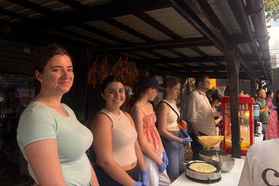 Frauen und Männer stehen an einem überdachten Stand und verteilen Crepes.