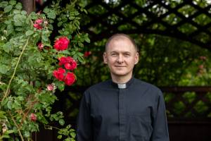 Das Bild zeigt Mykhaylo Plotsidem, Subregens des Priesterseminars L’viv, Theologe und Seelsorger. Neben ihm sind rote Blumen zu sehen.
