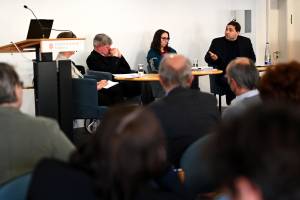 Das Bild zeigt Personen, die während einer Podiumsdiskussion angeregt miteinander sprechen