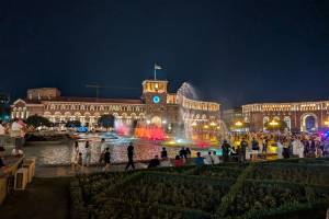 Der Republic Square in Jerewan, der armenischen Hauptstadt. Das Bild zeigt den Platz am Abend mit vielen bunten Lichtern, Waserspielen und Menschen, die flanieren und Fotos machen.